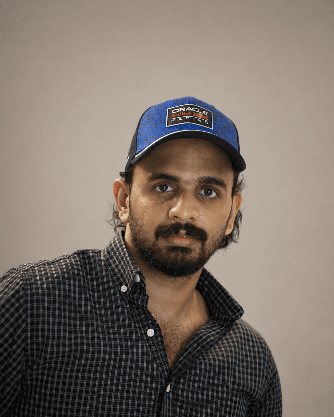 Ajmal K in a blue cap and check shirt against a studio backdrop